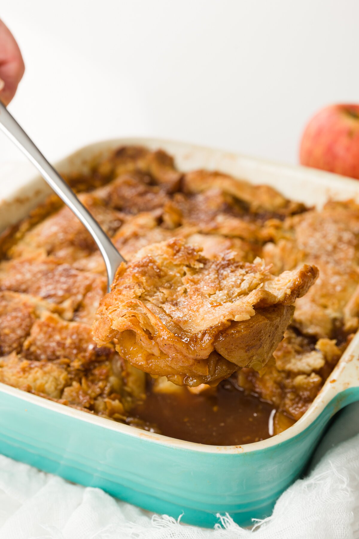 removing a piece of apple pandowdy from a pan with a spoon