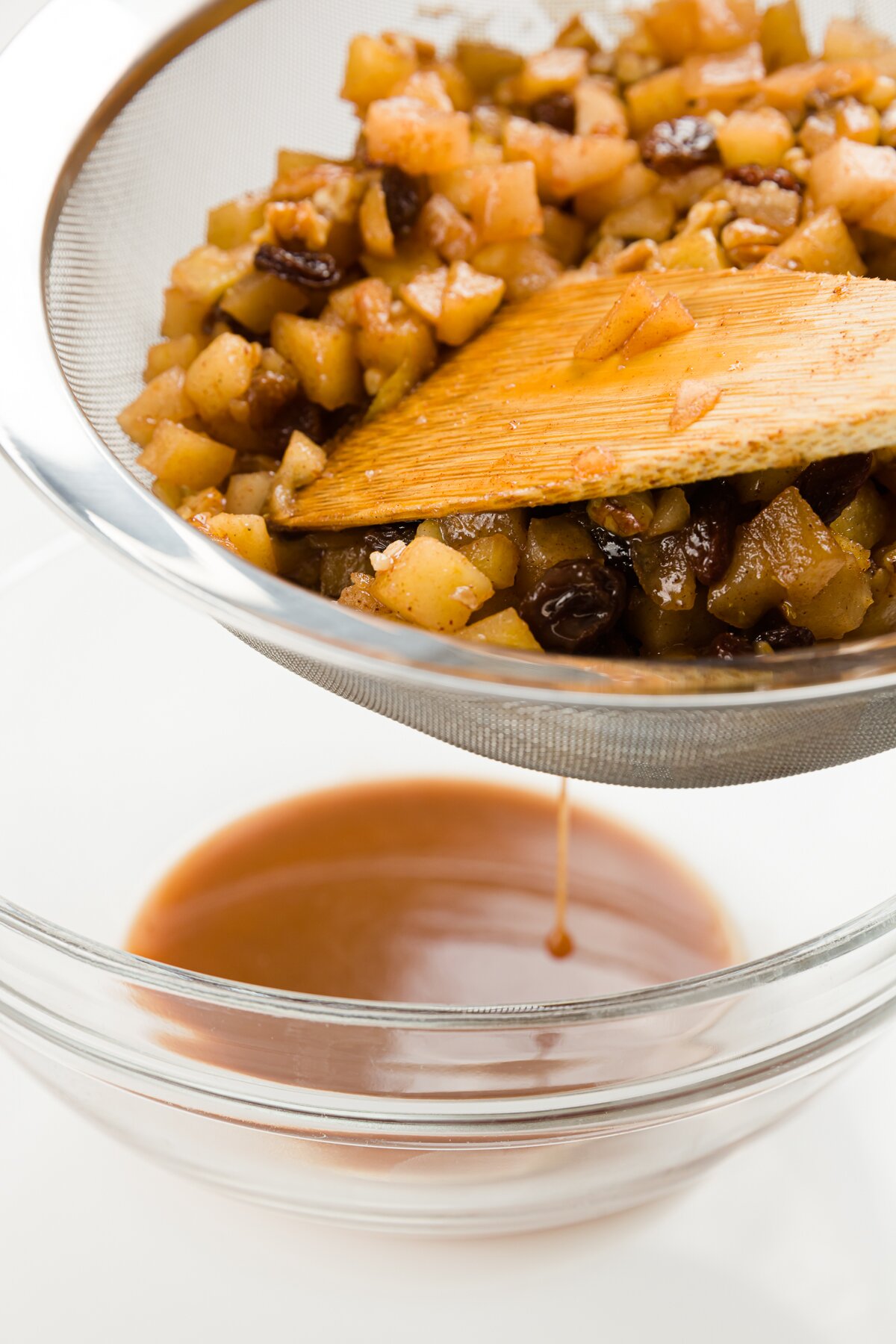 Apples in a sieve over a glass bowl with apple liquid in it