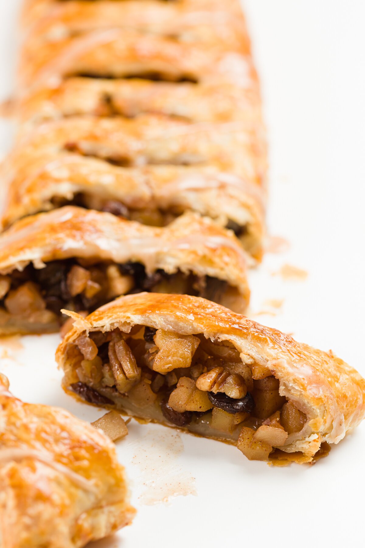 Slice of apple studel with the full strudel behind it
