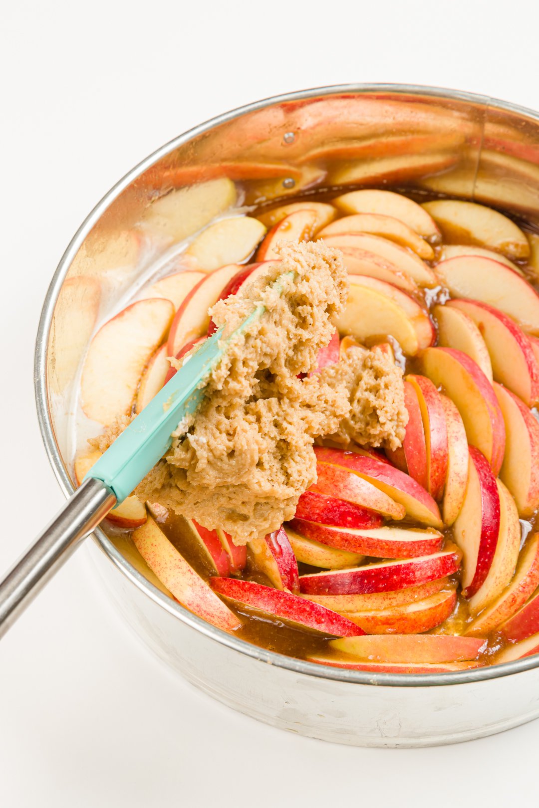Spreading cake batter over apples in a springform pan