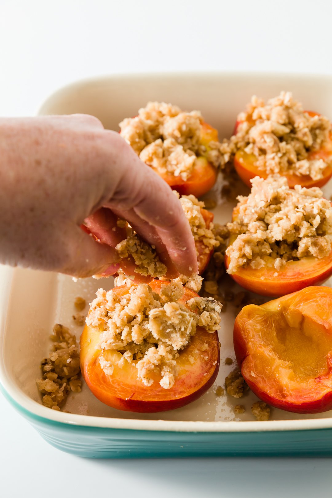 Filling baked peaches with crumb topping