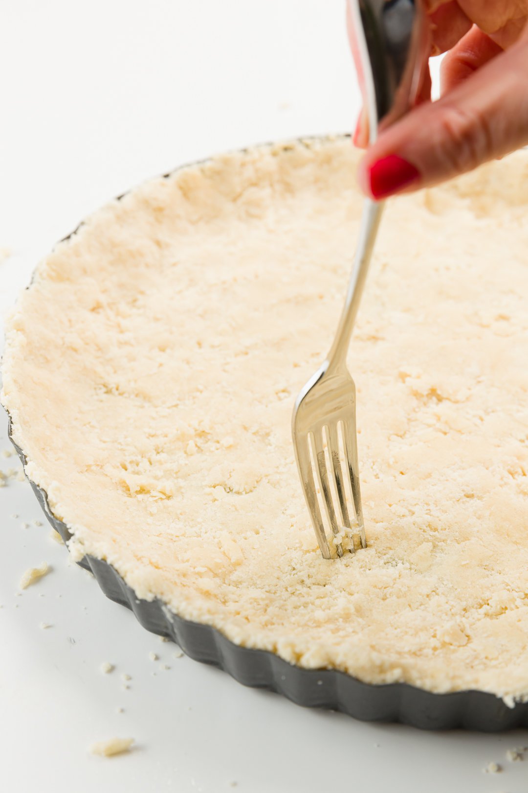 salted honey crust before it's baked in a tart pan getting poked with fork