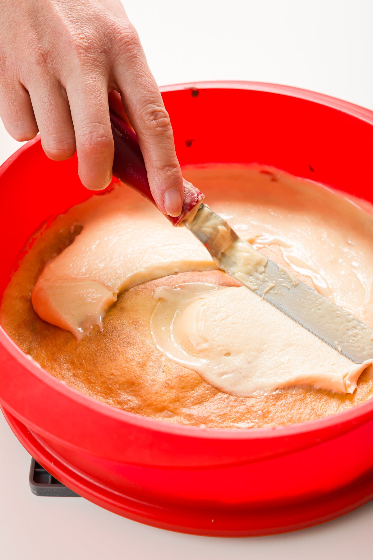 Spreading batter over cooked later with an offset spatula