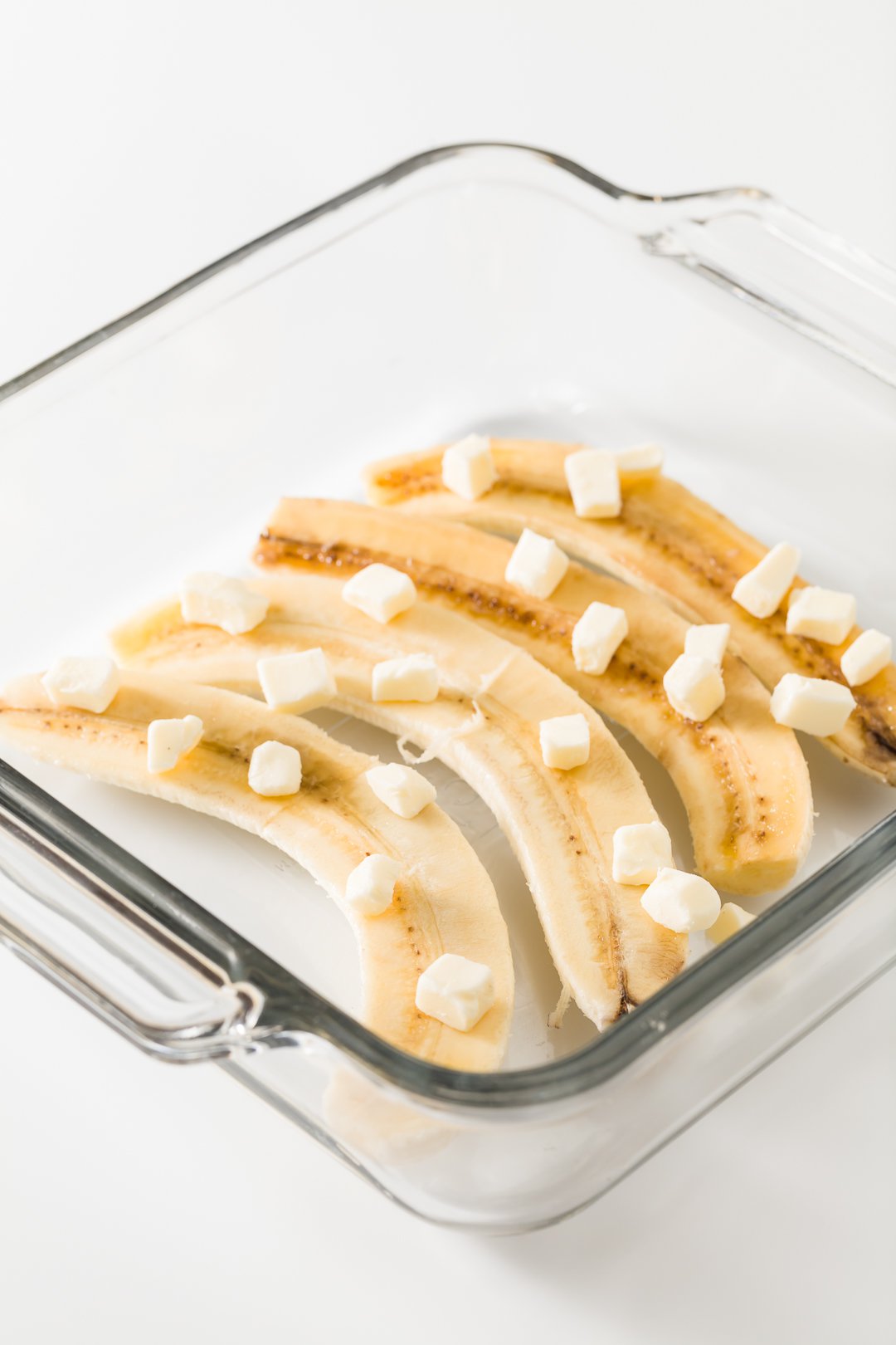 bananas in a glass dish topped with butter
