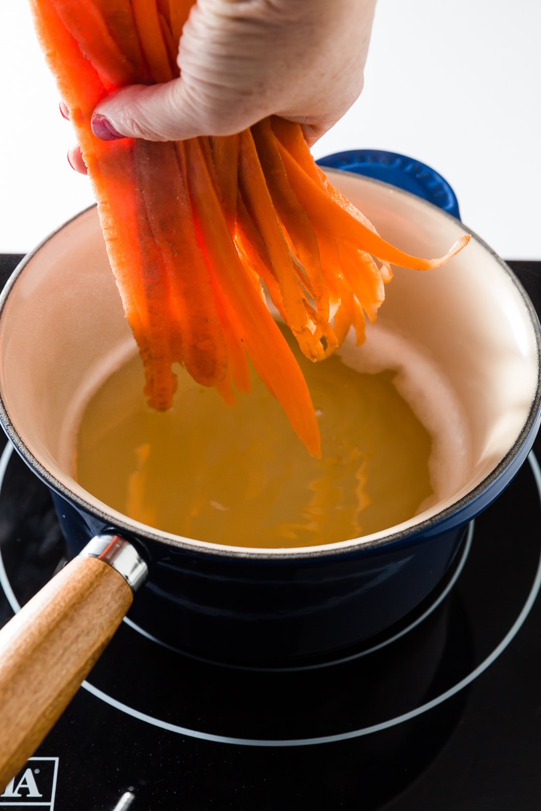 Adding carrot ribbons to hot sugar mixture.