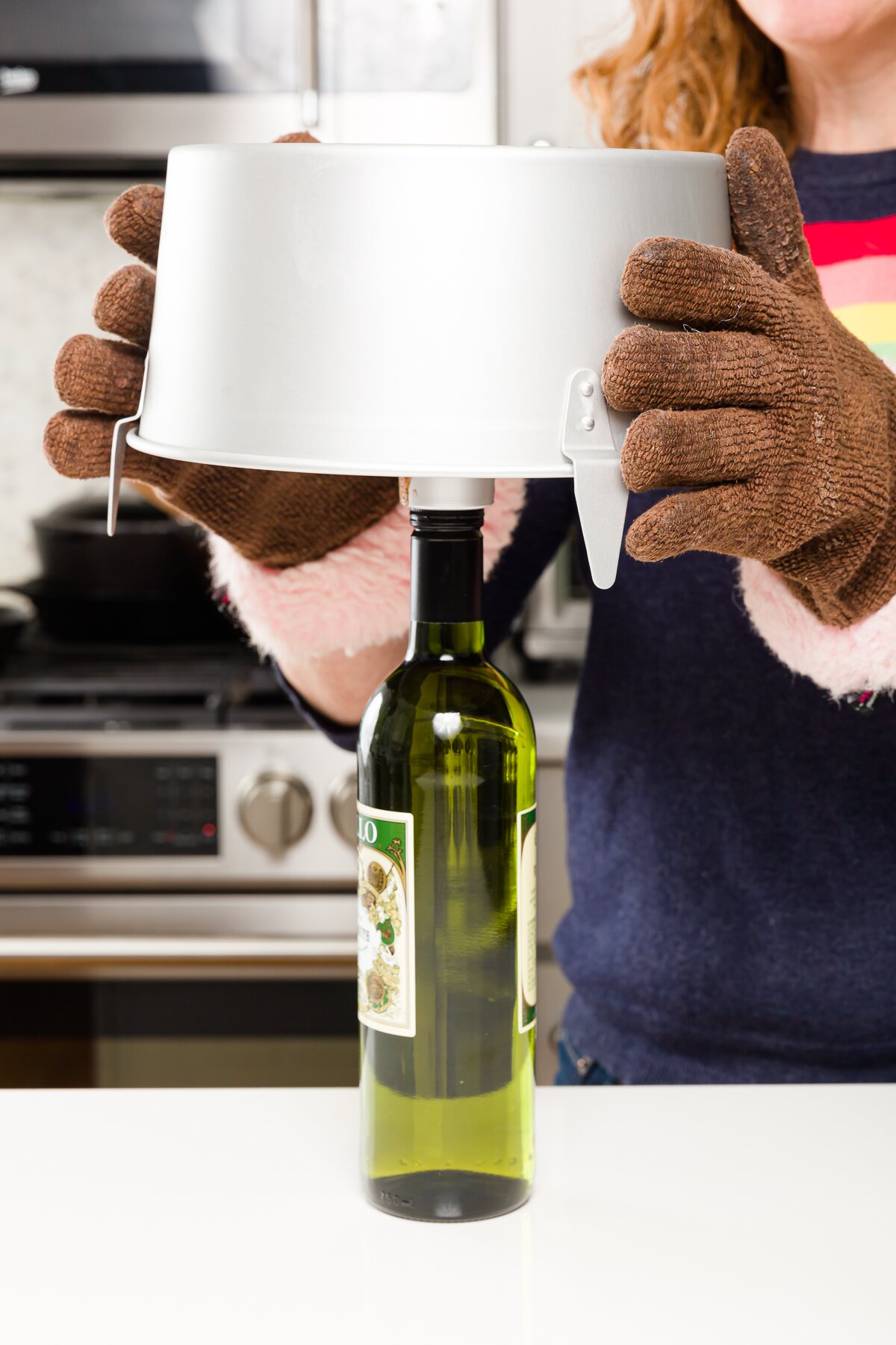 Setting hot angel food cake pan over a green wine bottle