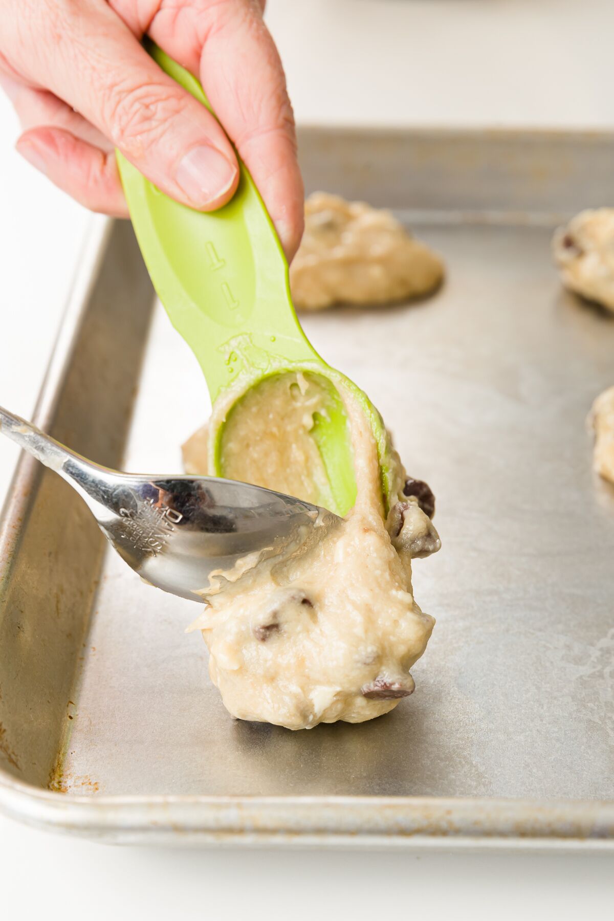 Adding cookie dough to a cookie sheet using two spoons