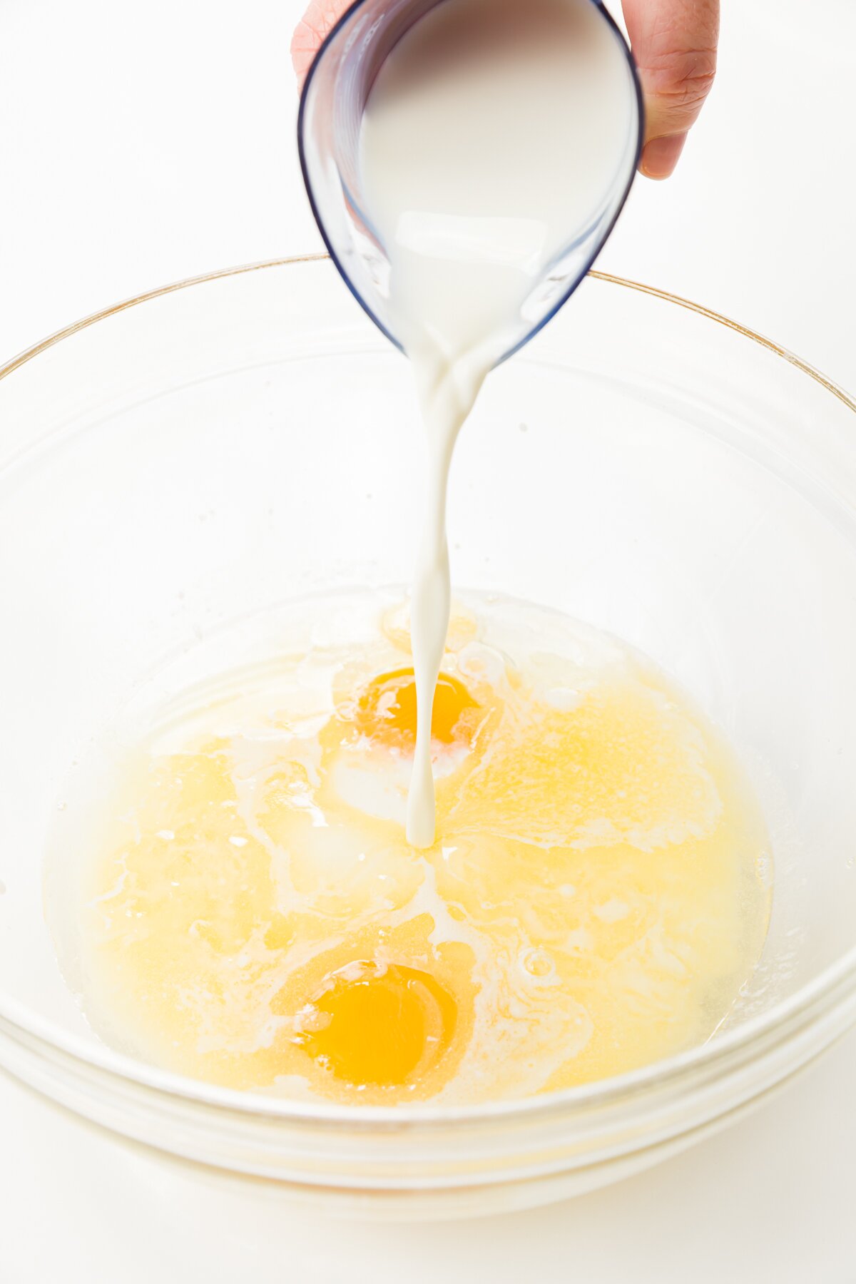 pouring milk into a bowl with eggs