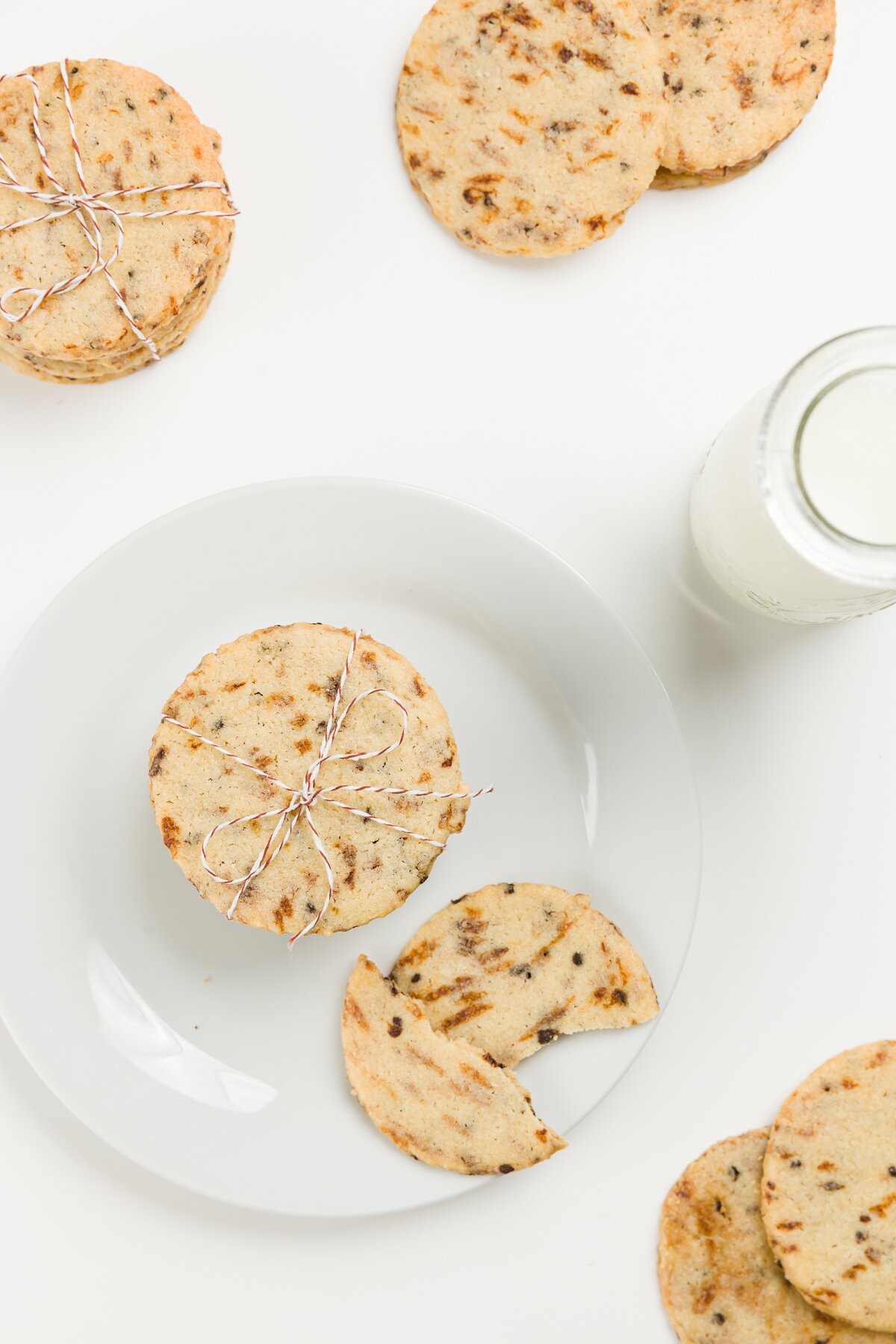 Top down photo of coffee cookies on a plate with milk and one broken cookie