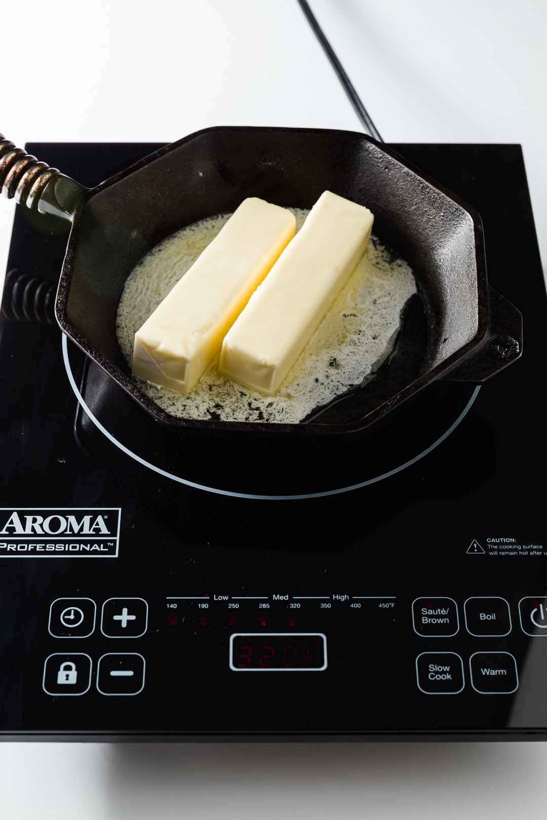 Two sticks of butter starting to melt on a skillet