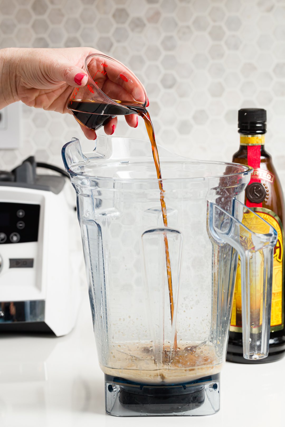 Stef pouring Kahlua into a blender to make a frozen mudslide cocktail