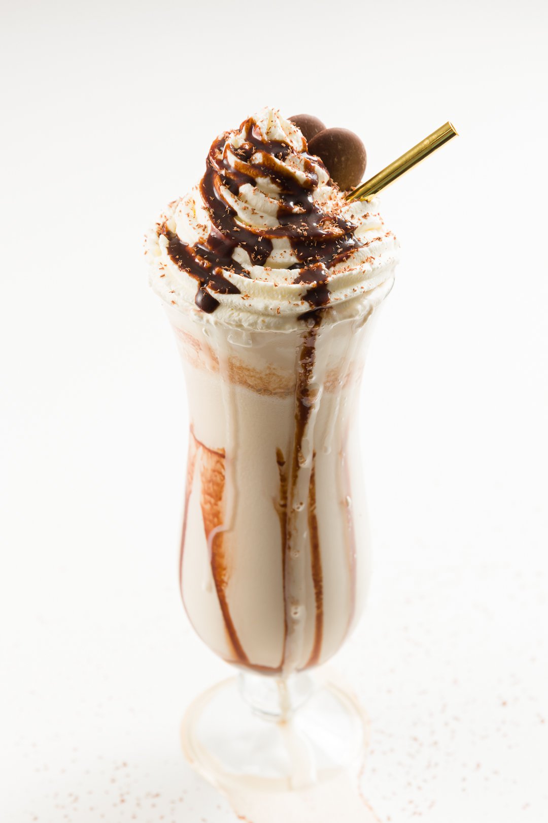 frozen mudslide cocktail topped with whipped cream, chocolate shavings, chocolate sauce, and chocolate discs