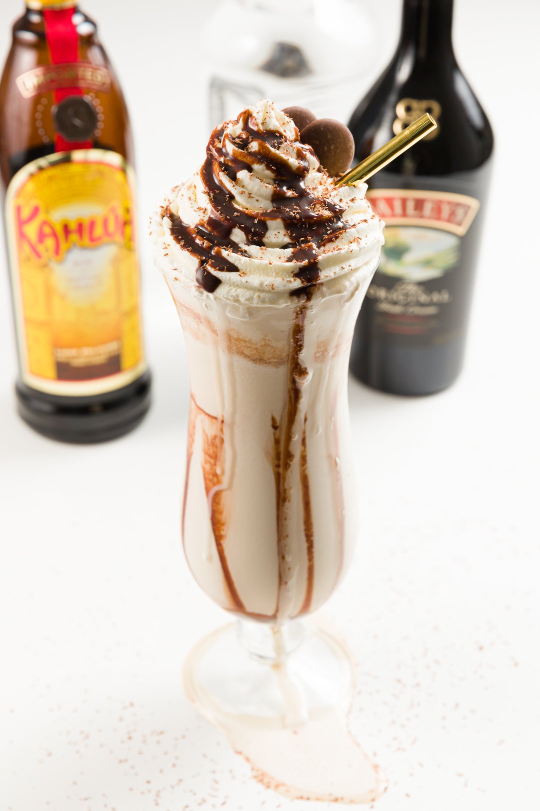 frozen mudslide cocktail with bottles of Kahlua, Baileys Irish Cream, and vodka in the background