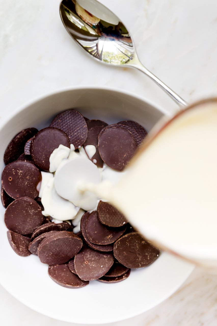 Hot cream being poured over dark chocolate discs