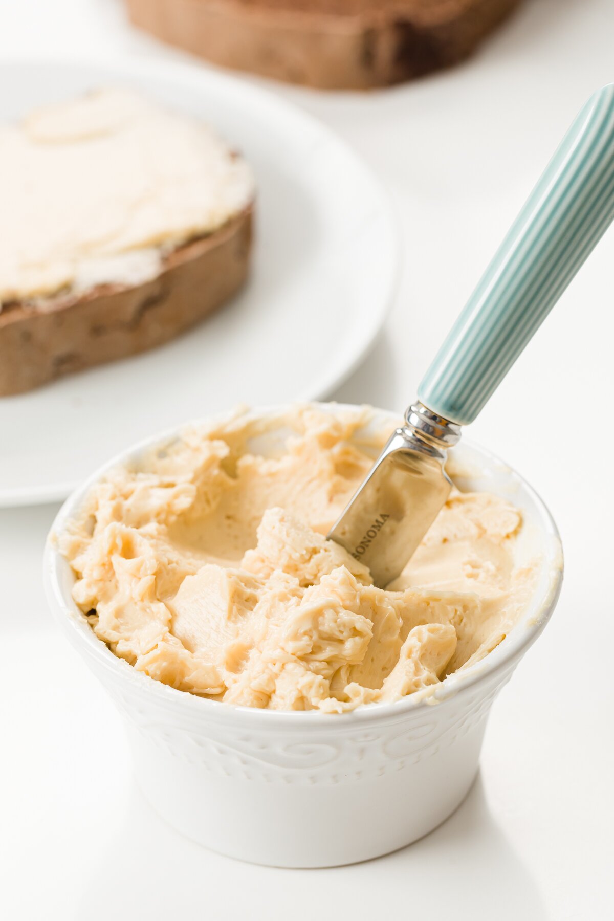 Maple butter in a ramekin with a knife in it and toast in the background