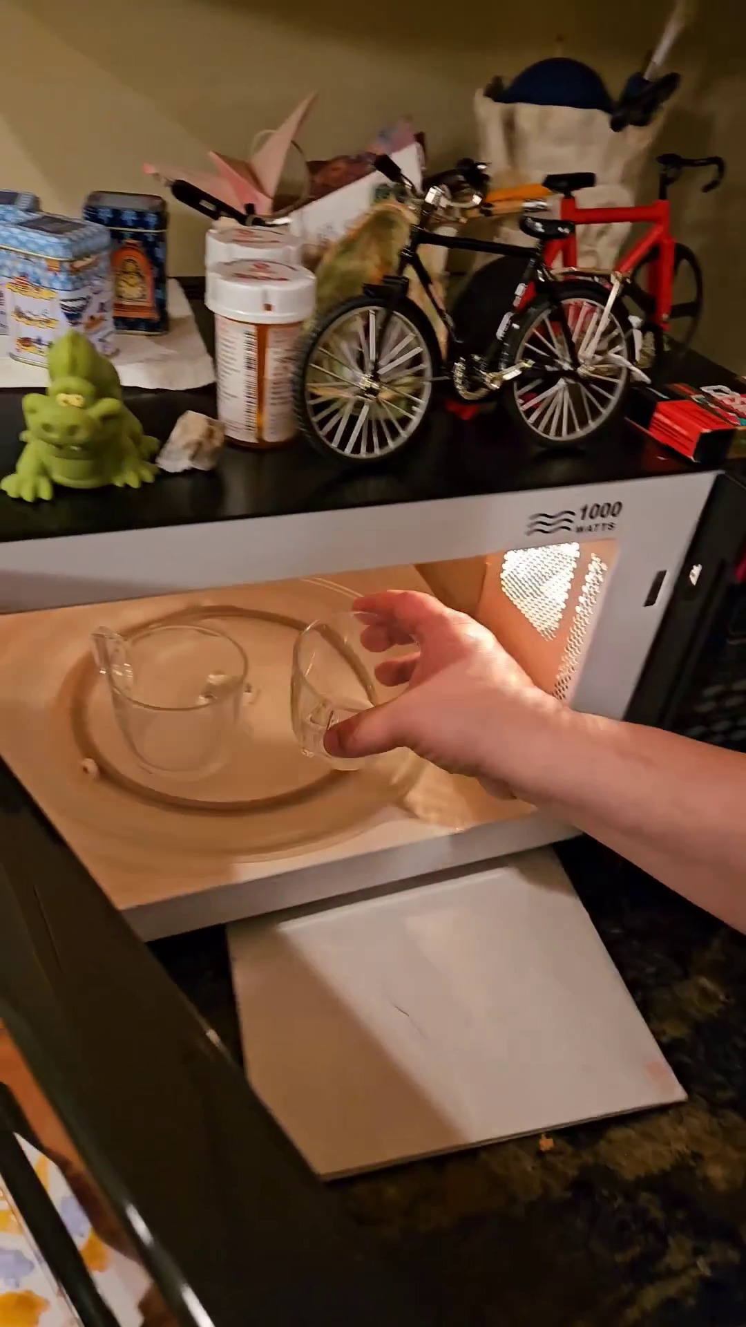 Placing glass cups with dissolved sugar in the microwave.