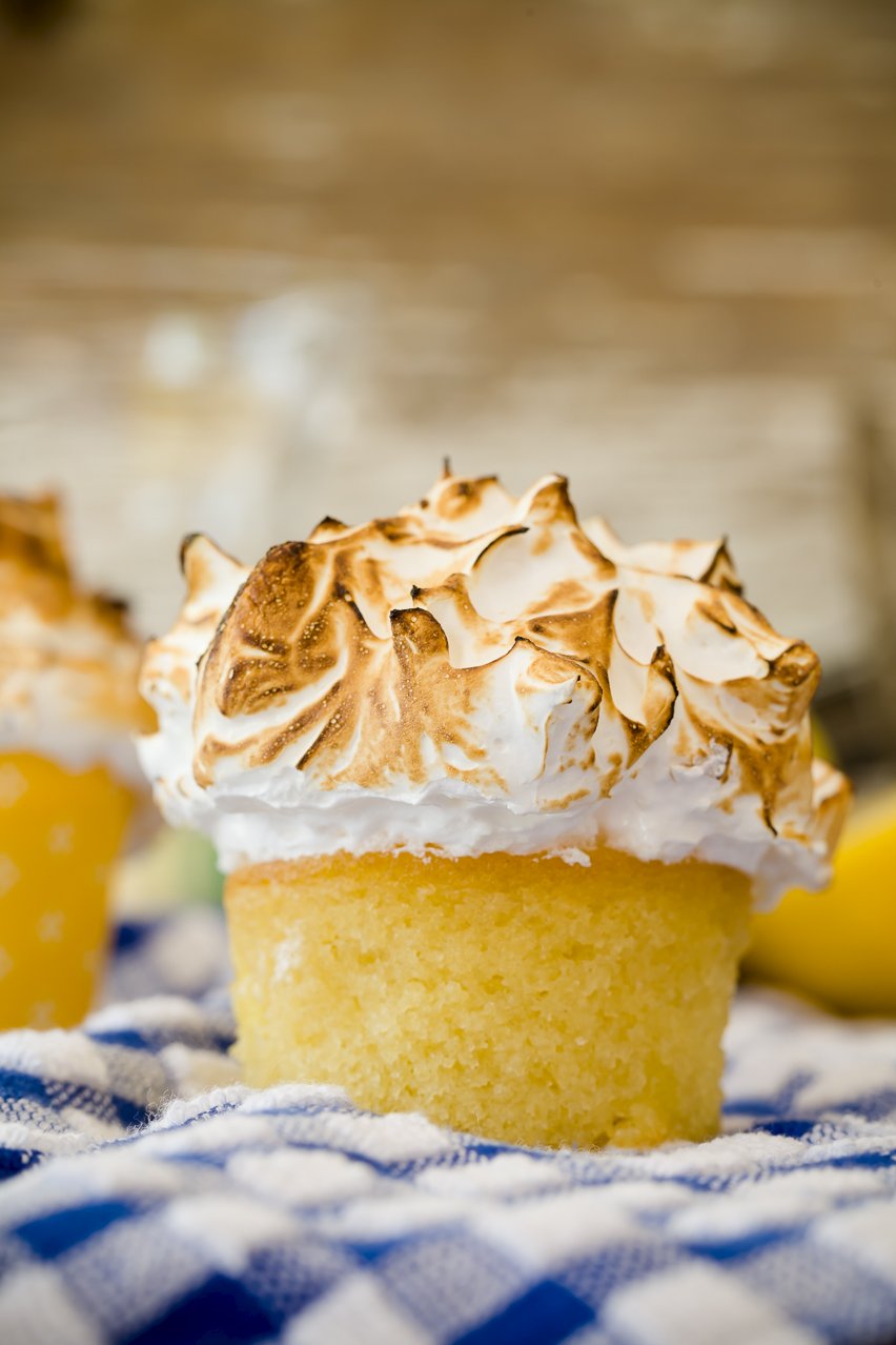 Mile-high lemon meringue cupcakes on a checkered tablecloth