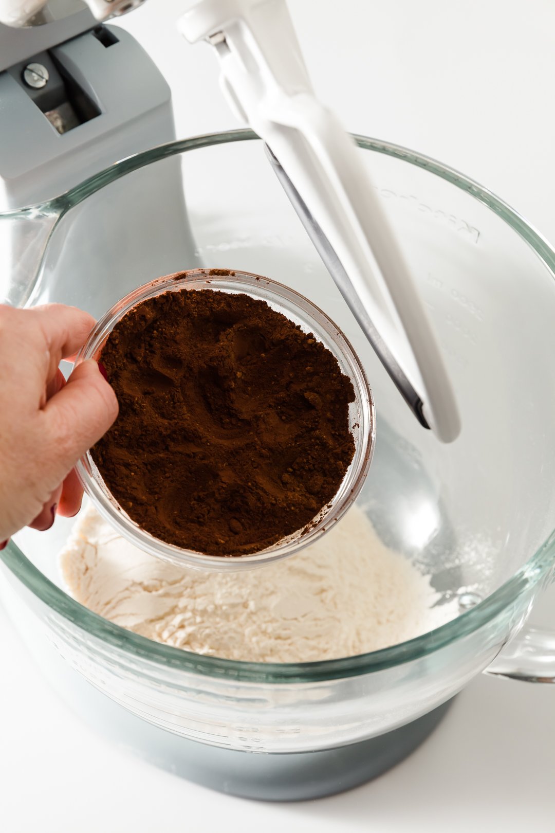 Dark cocoa powder being adding to a mixing bowl