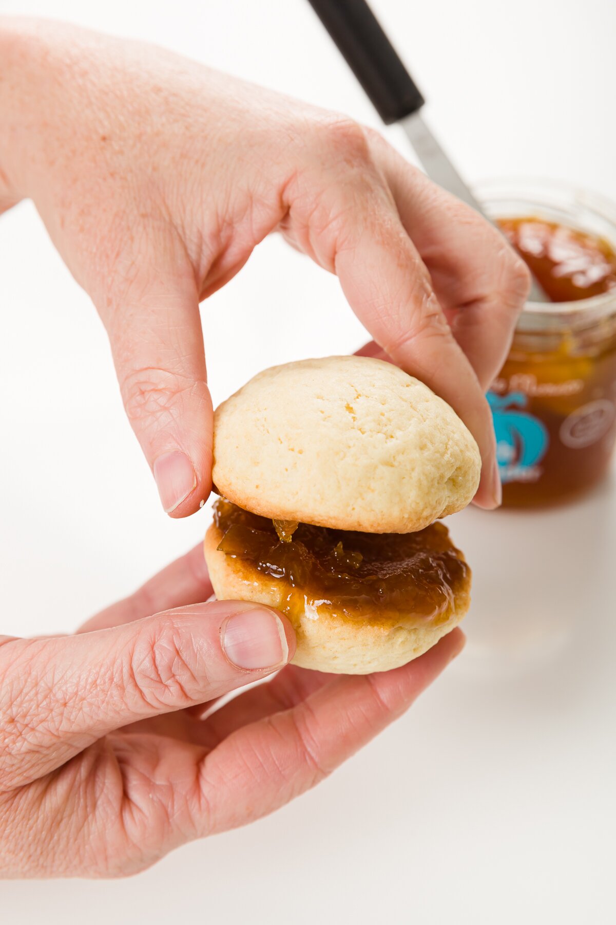 Two cookies being sandwiched together with jam