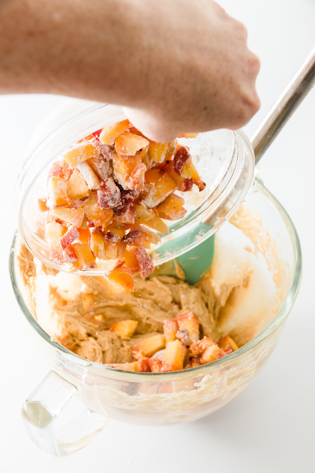 Peaches tossed in flour being added to peach muffins