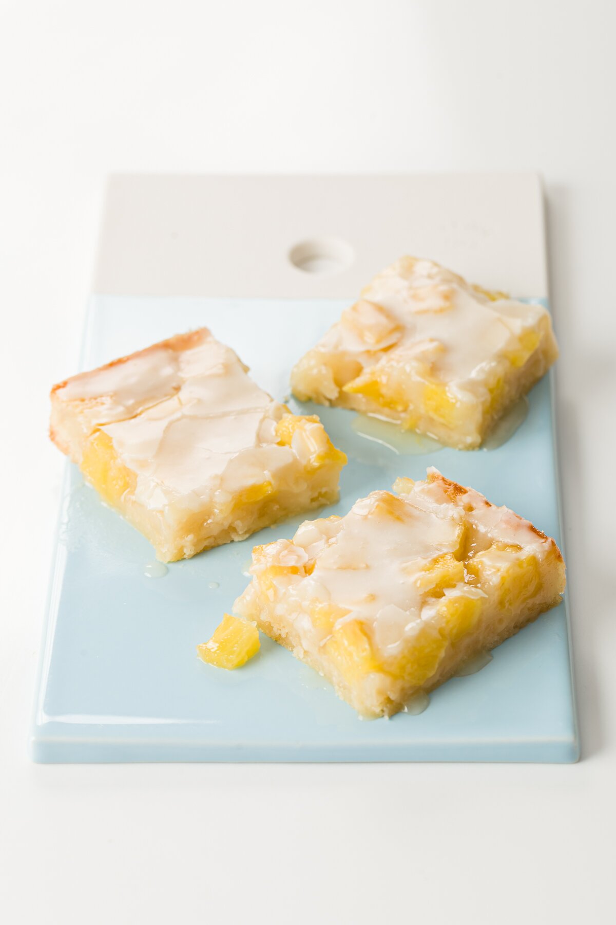 3 glazed pineapple bars on a blue and white ceramic slab