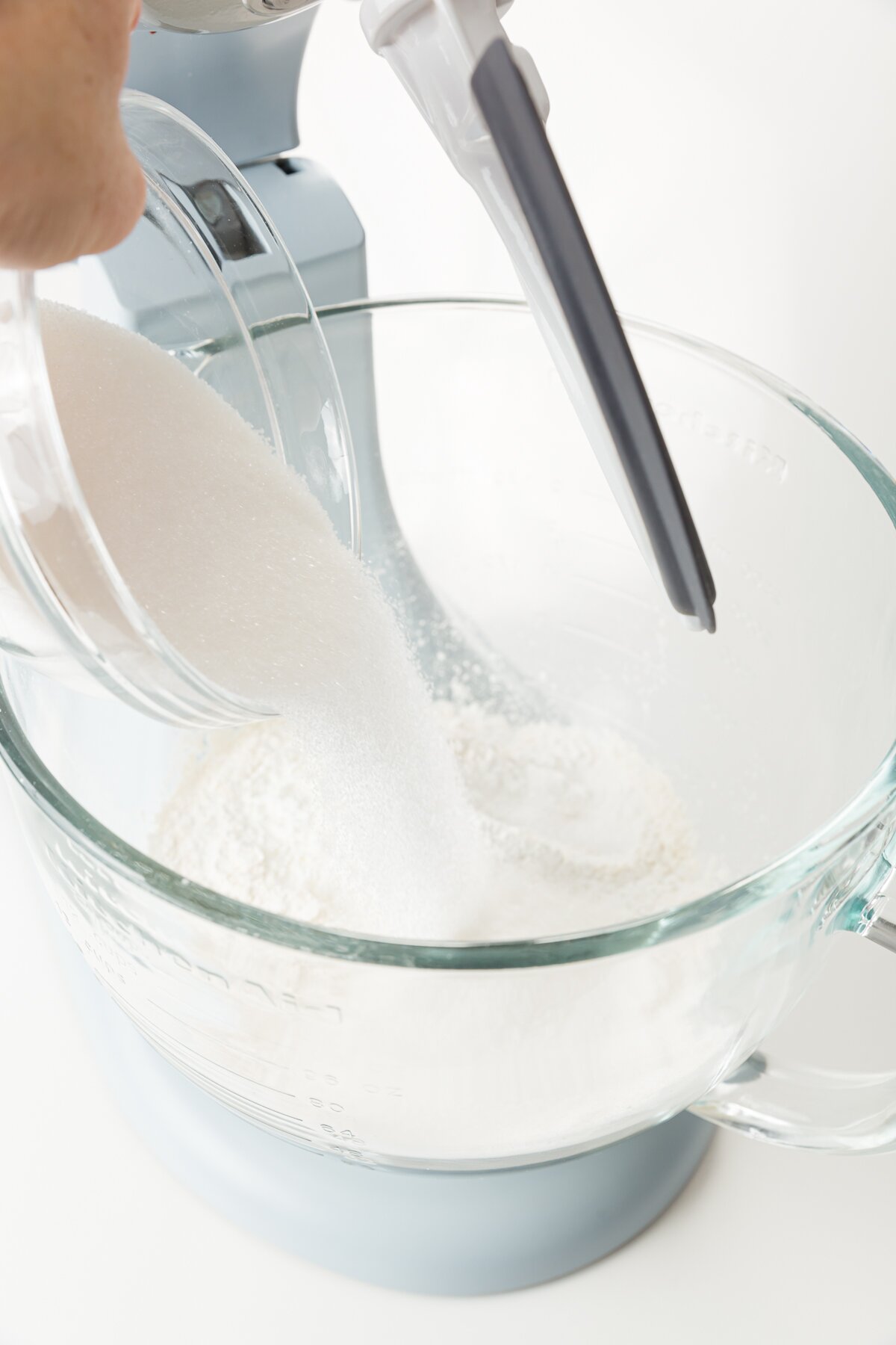 Stef adding sugar to dry ingredients in a stand mixer