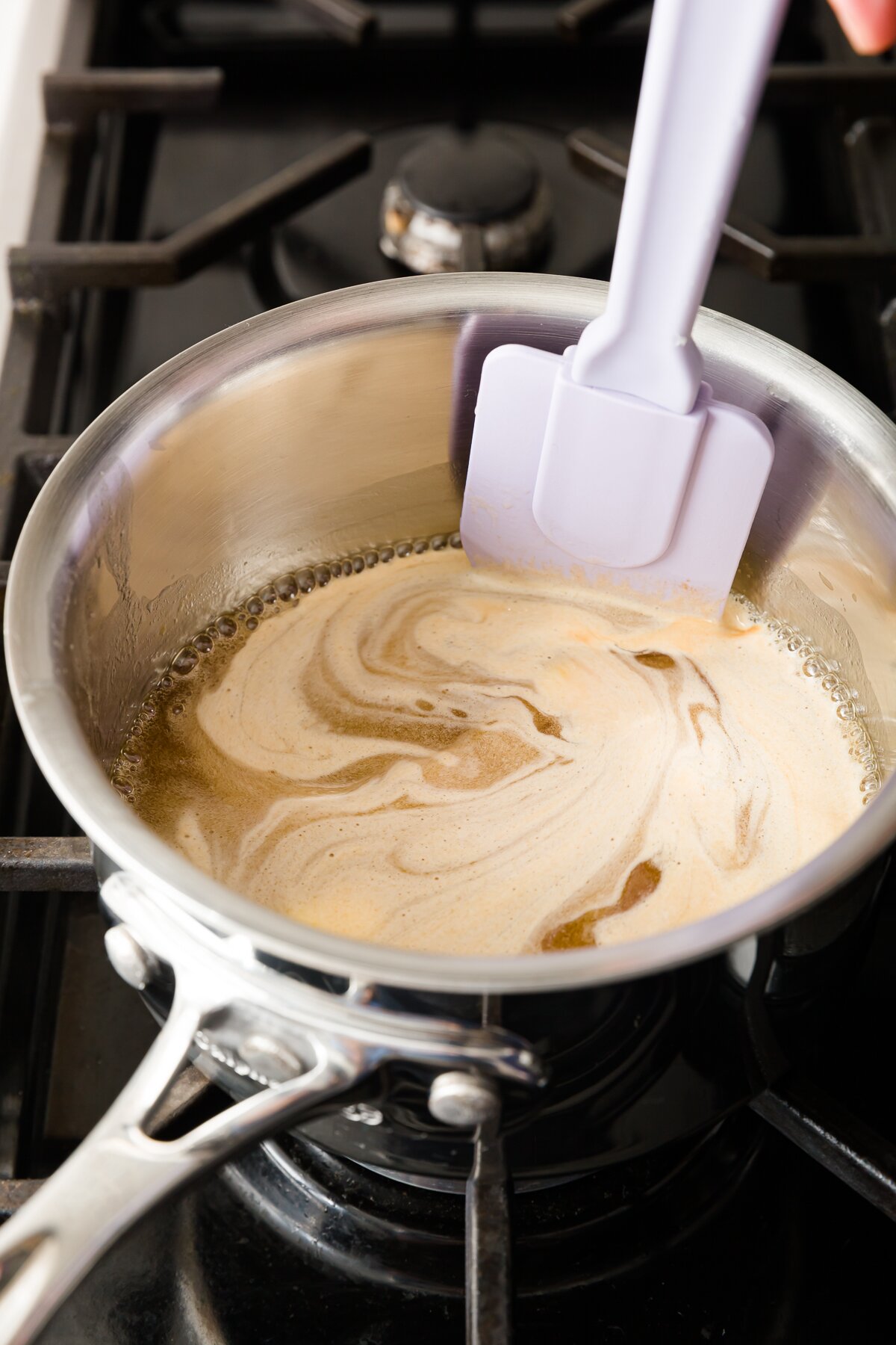 looking down into a pot where Stef is stirring ingredients of rum syrup