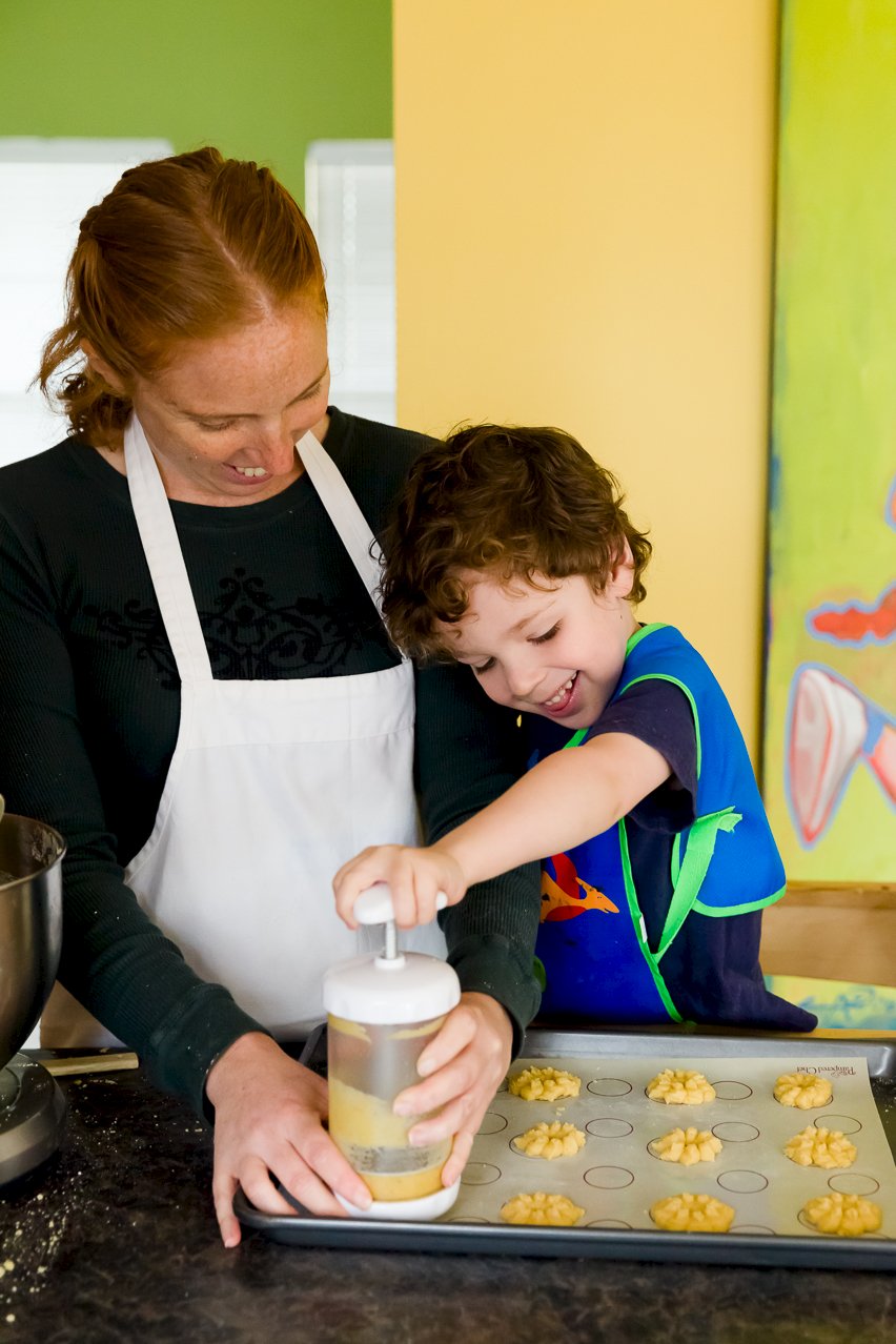 Pressing cookies onto a cookie sheet with a cookie press