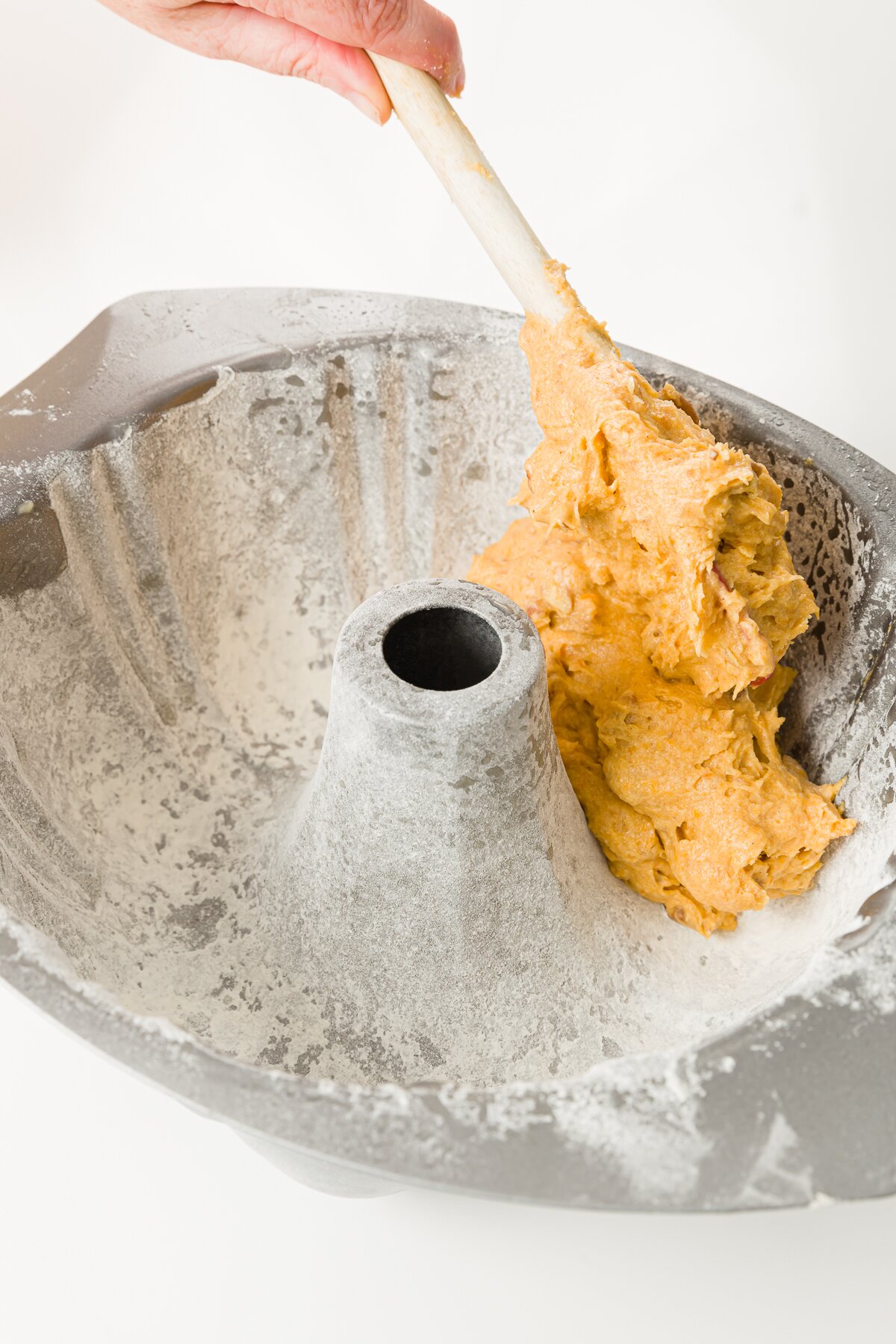 Filling a greased and floured Bundt pan with batter