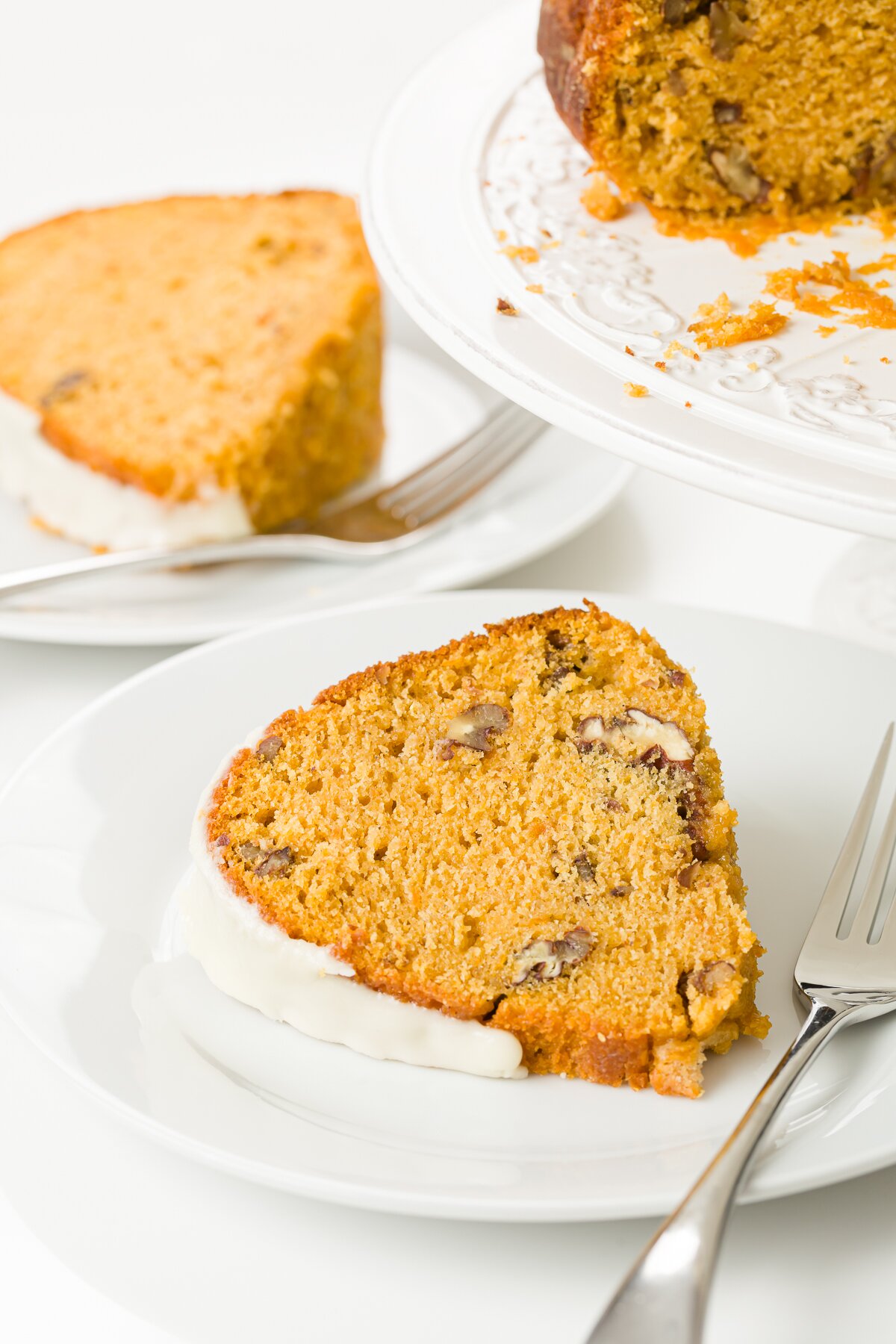 Close up shot of a slice of cake with another slice and a section of the full cake showing the background