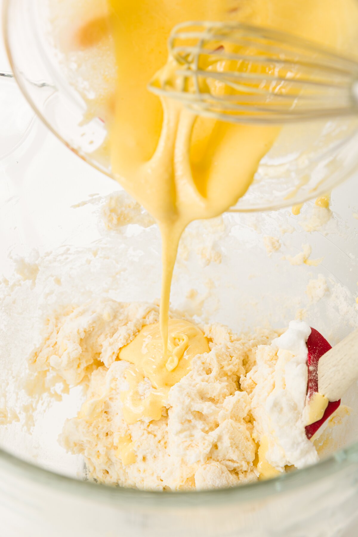 tight shot of Stef pouring the egg yolk mixture into the tiramisu cupcake batter