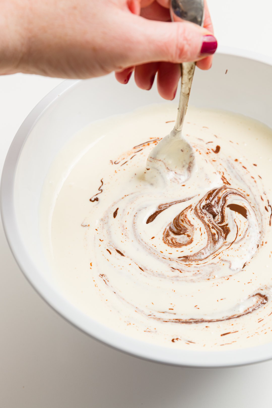 looking into a bowl where Stef mixes melted chocolate into the batter