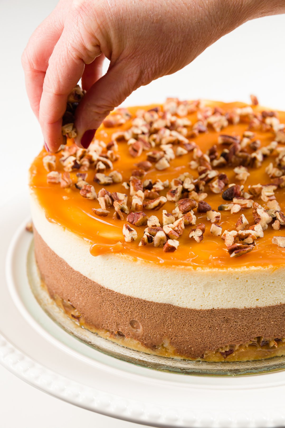 adding pecans to the top of turtle cheesecake